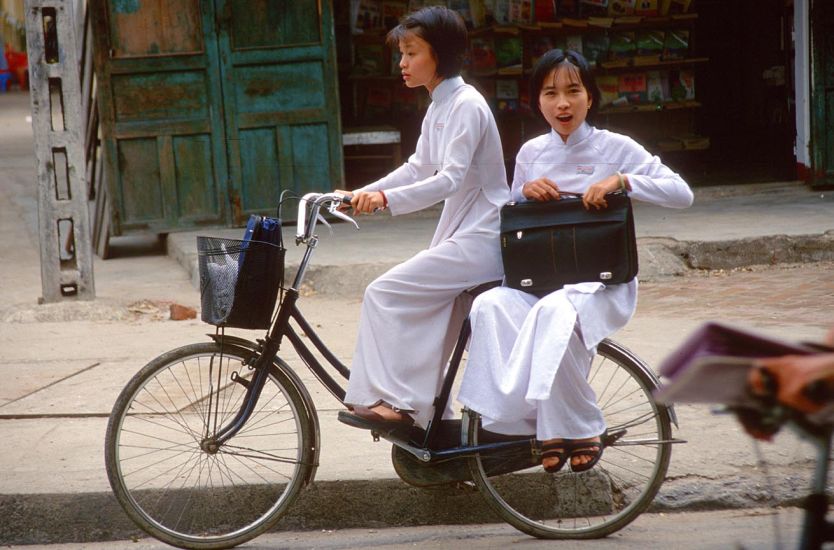 Vietnamese Girl Cyclists in traditional ( ao dai ) dress